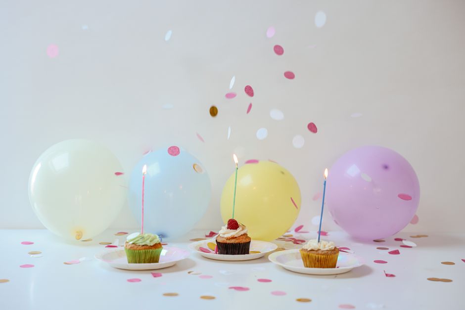 Vibrant birthday setup with cupcakes, balloons, and confetti on a table.