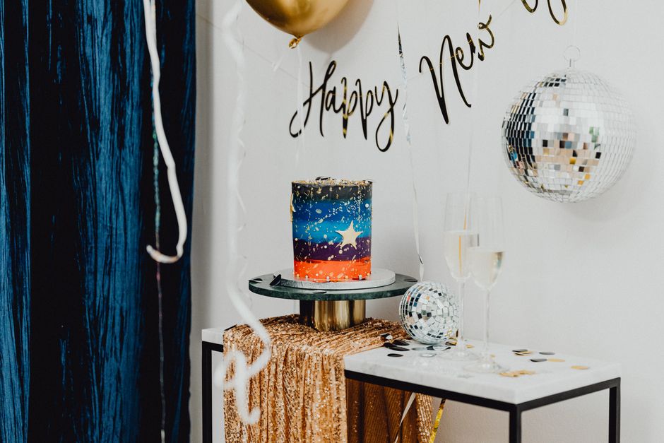 Colorful new year's party setup featuring cake, disco balls, and champagne.