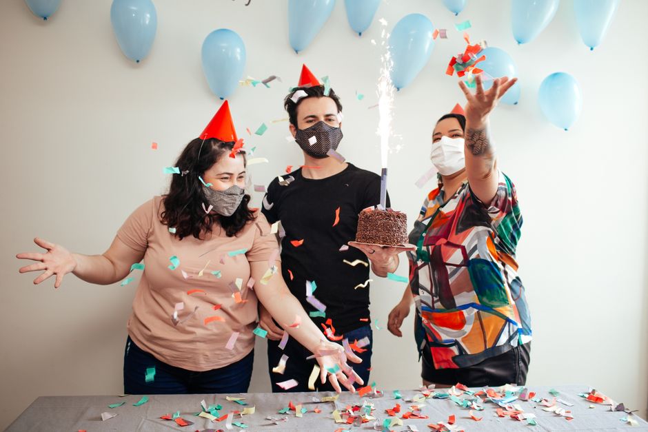 Celebration with masks, balloons, cake, and confetti indoors. Party vibe.