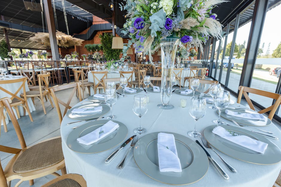 Beautifully arranged wedding table with floral centerpiece, cutlery, and wineglasses in a luxurious venue.